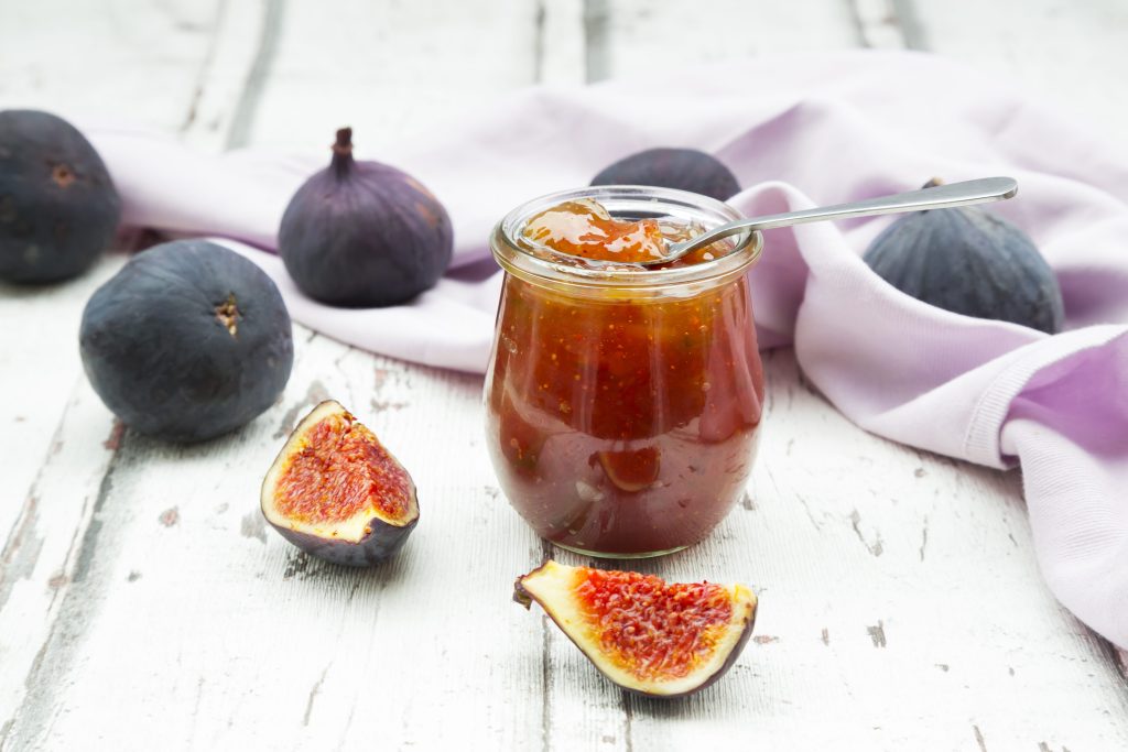 Organic figs and a glass of fig jam on a wood