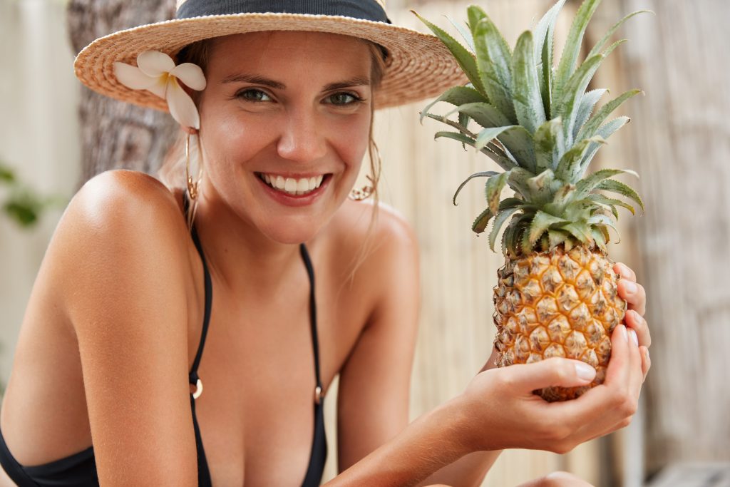 Woman smiling holding pineapple