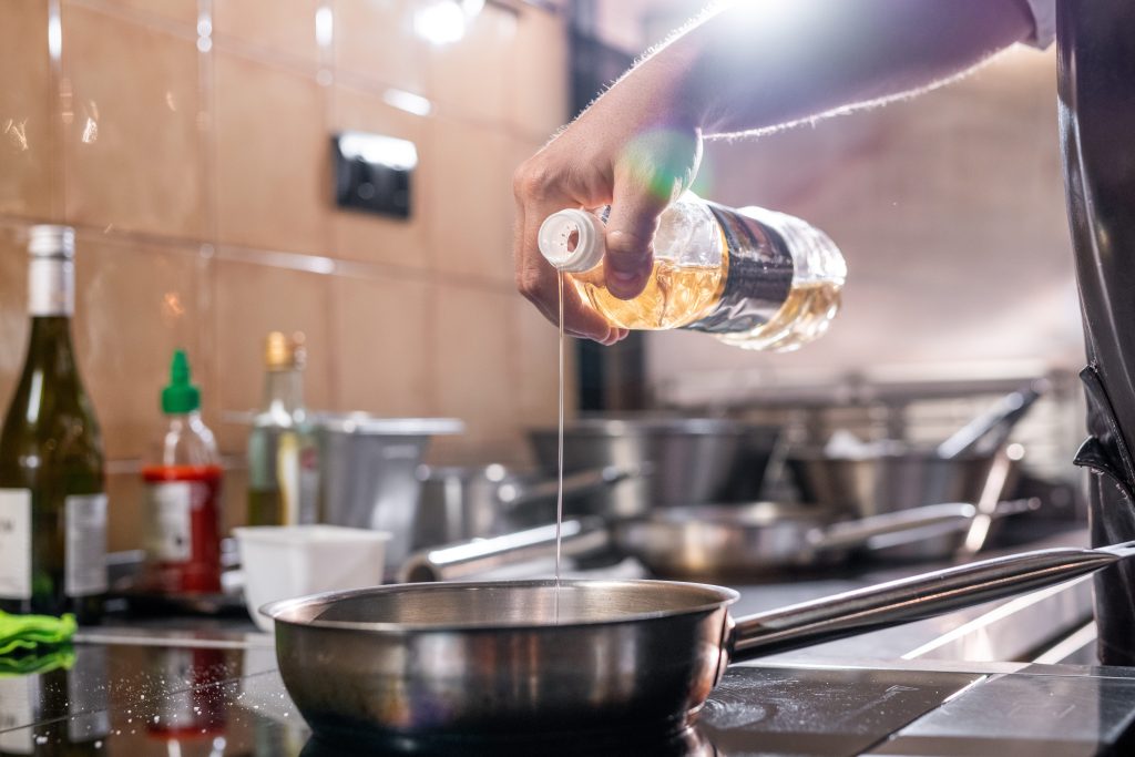 Chef using cooking oil to make meal