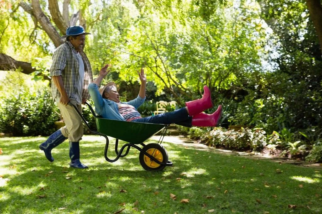 Older couple pushing each other in wheelbarrow