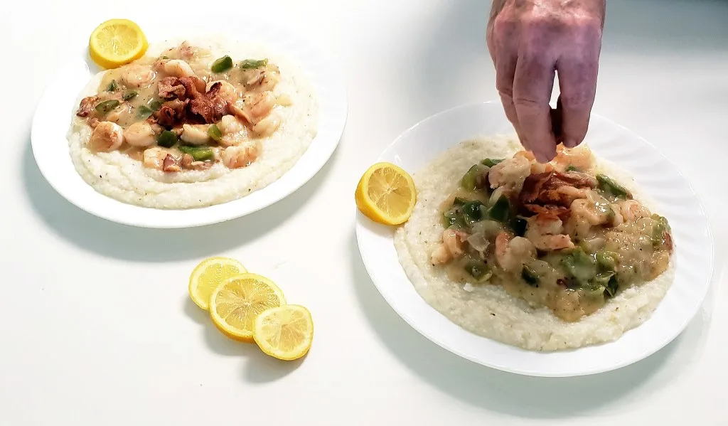 Man sprinkling spices on shrimp and grits