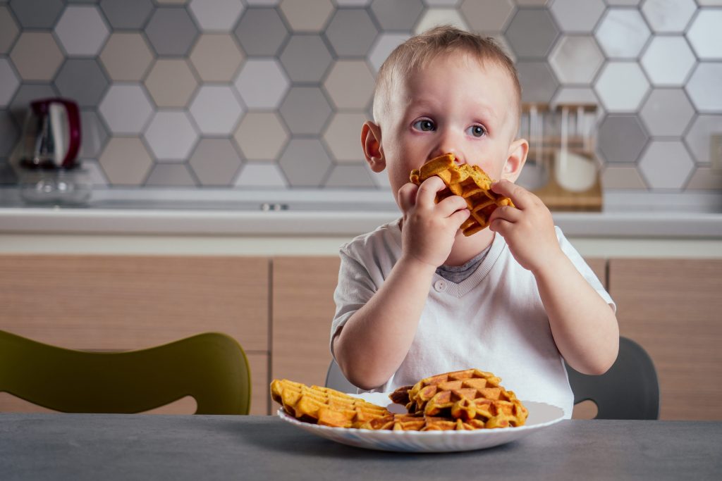 Little boy eating waffles 