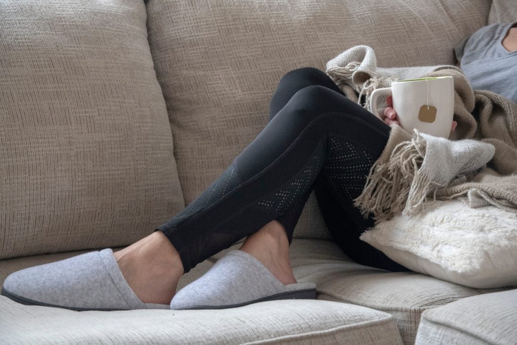 Woman sitting on couch wearing slippers