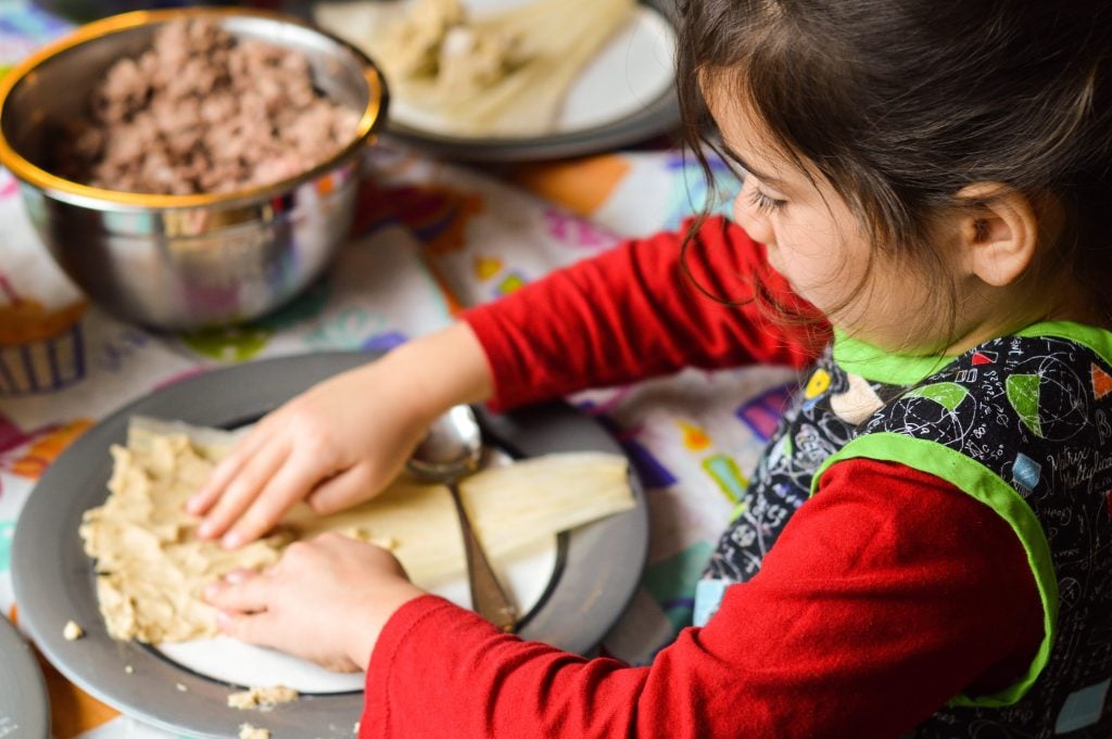 Little girl making tamales at Christmas.