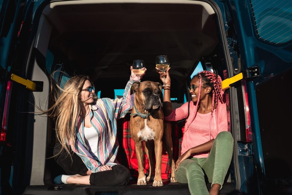 Friends drinking wine in the back of camper van while boondocking