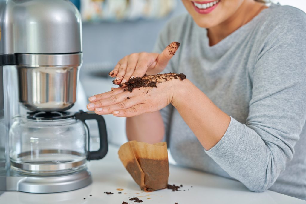 Woman using coffee grinds to exfoliate skin