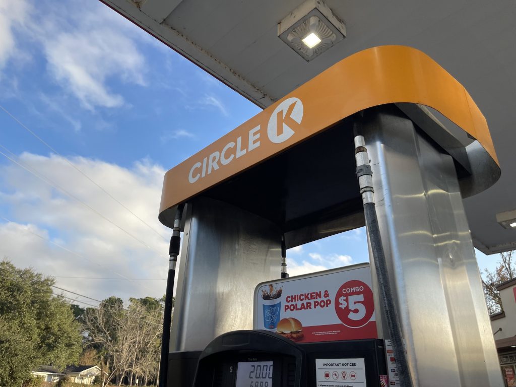 A photo of a Circle K gas pump with blue sky and white clouds behind it.