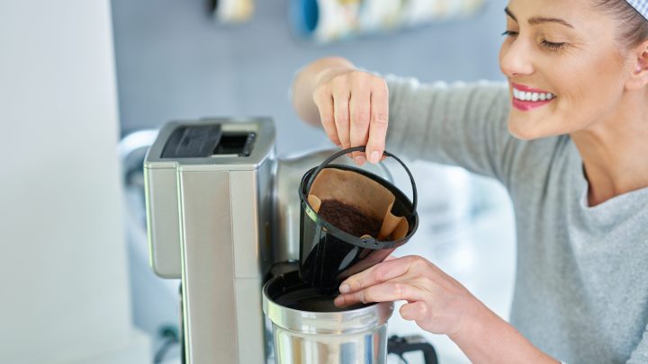 Woman removing coffee grounds from machine to dispose