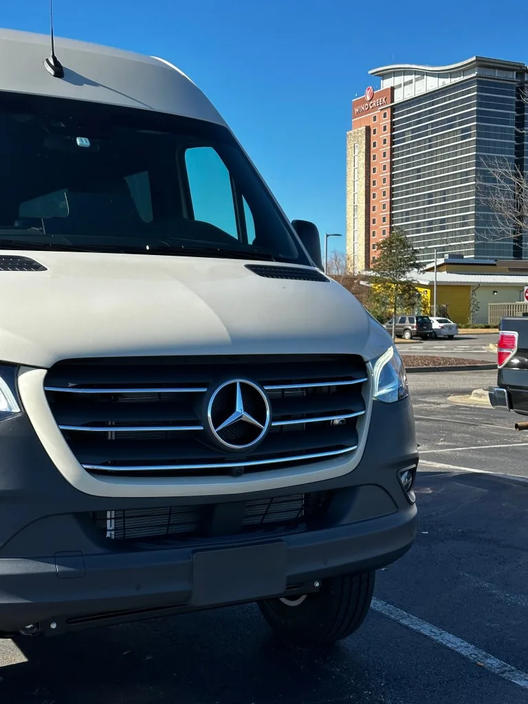 A photo of a campervan in a hotel parking lot, potentially staying overnight.