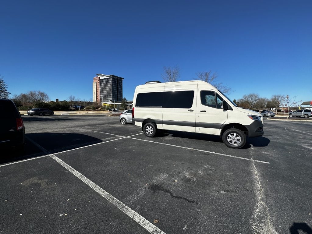 A photo of a campervan in a hotel parking lot, potentially staying overnight.