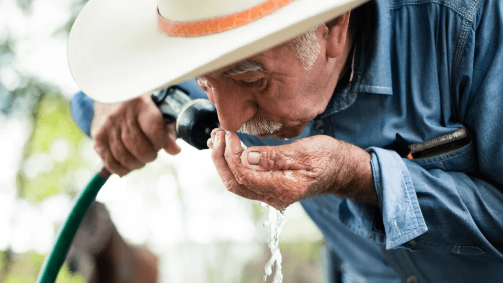 Older man drinking from water house