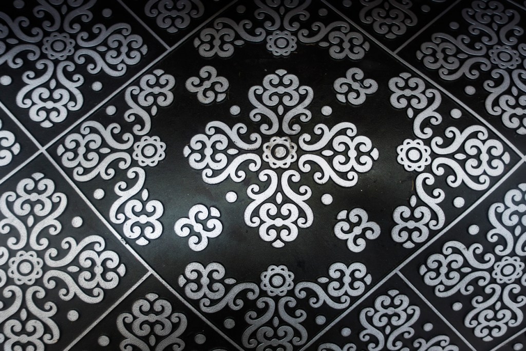 A silver and black floral design on an outdoor doormat