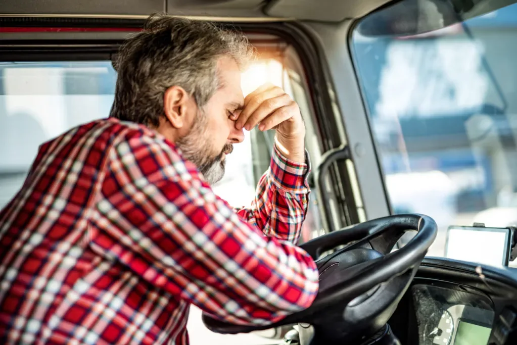 A stressed man sitting at the wheel of an RV. Stress is one of the reasons for the RV decline.