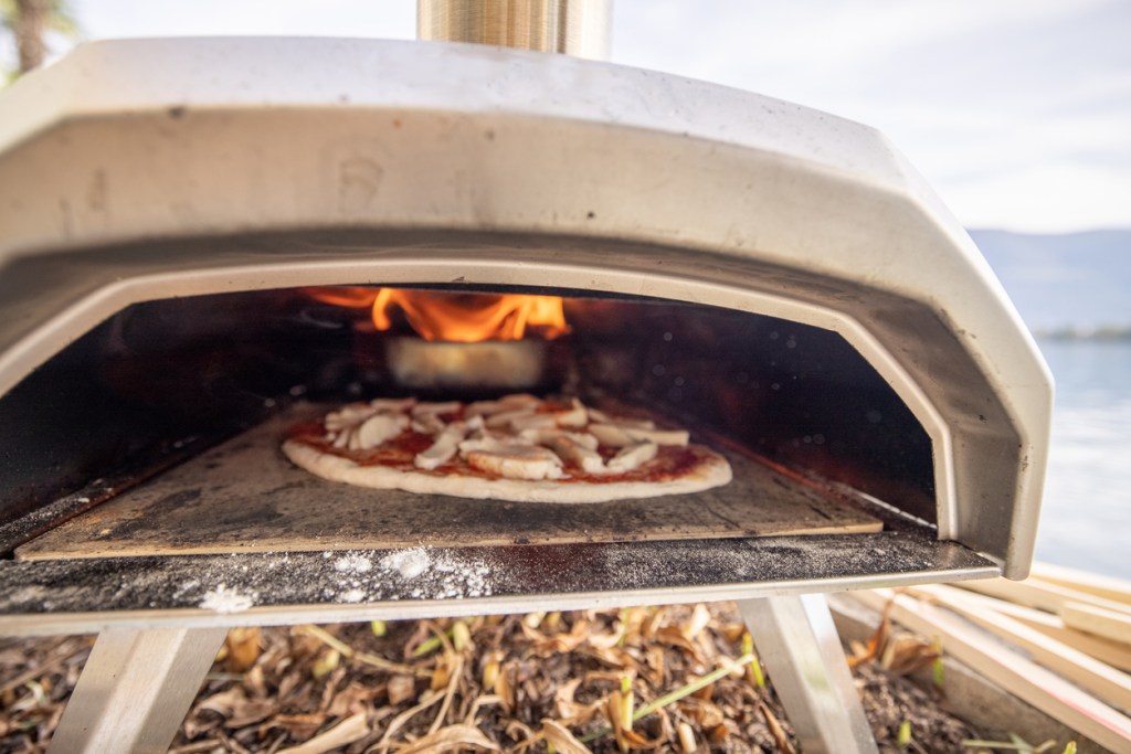 A close-up view of a portable pizza oven with a pizza baking inside