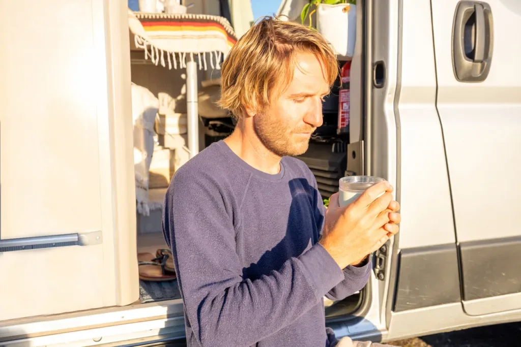A man looking at a glass of water like he's not sure he wants to drink it. It may have come from his RV's freshwater tank