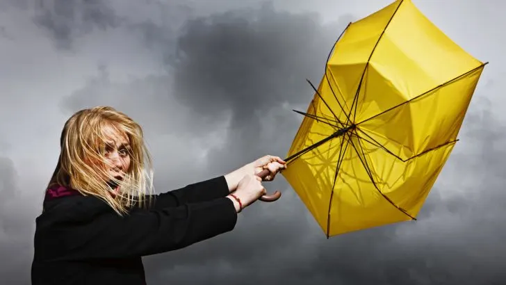 A woman with a yellow umbrella that strong winds turned inside out