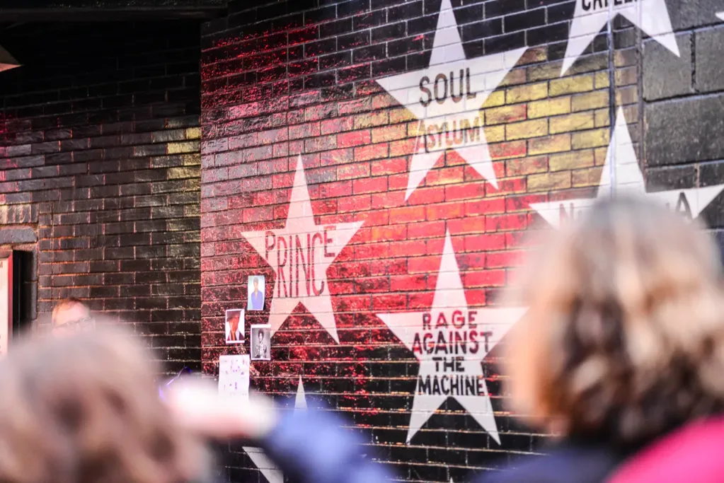 White stars painted on a black brick wall, including the names Prince, Soul Asylum, and Rage Against the Machine