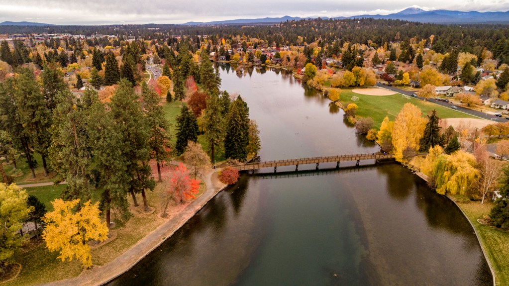Looking down on Deschutes River in Bend Oregon lined with autumn colored trees. Fall is a wonderful time to experience Bend.