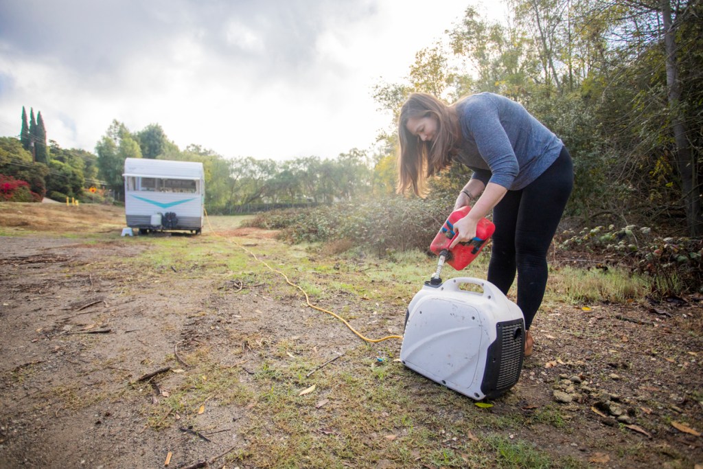A young woman setting up camp in the wilderness with her trailer