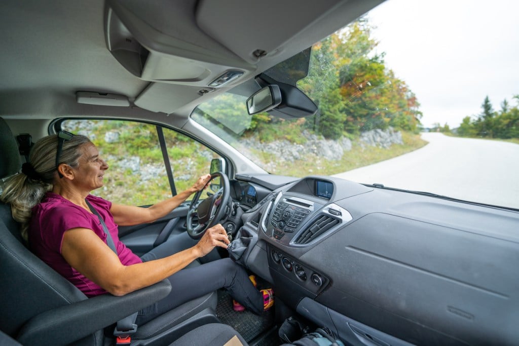 Woman Driving her Camper Van up Mountain Road. You might want to look into a driving course if you'll be a solo traveler.