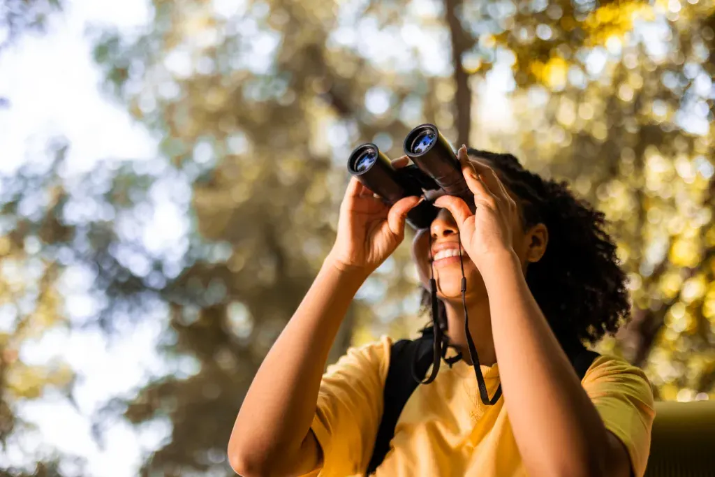 A woman hiker with binoculars. You can birdwatch at Bosque Del Apache Wildlife Refuge near Albuquerque, New Mexico