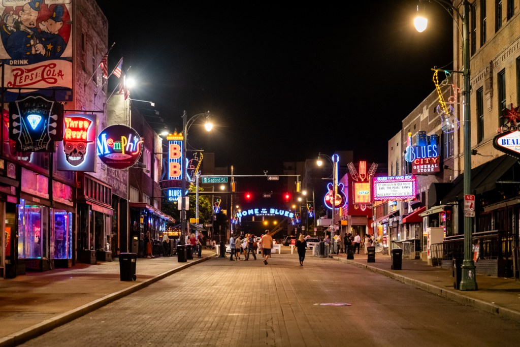 Nighttime photo of neon signs of bars and music venues on Beale Street in Memphis where the blues was born.