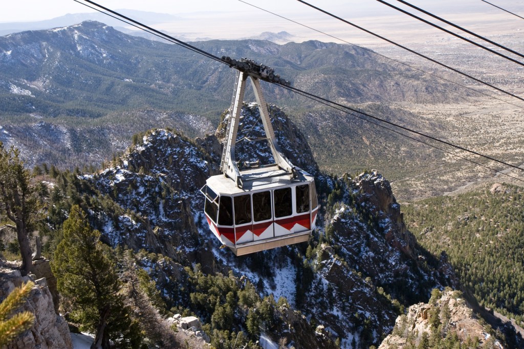 The Sandia Peak Tramway (Cable Car) approaching the top of Sandia Peak. The mountains and outskirts of Albuquerque far below can be seen in the distance. This is a great day trip from Albuquerque!