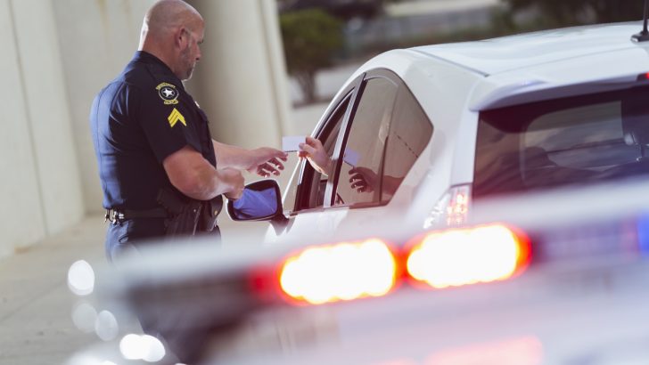 A police officer checking a driver's license of someone he has pulled over.