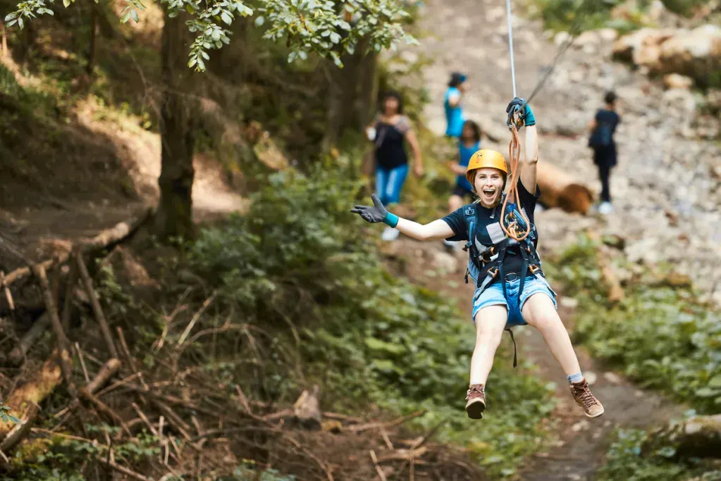 A happy woman ziplining. Glacier Highline Adventure Park is a great day trip near Whitefish, Montana.