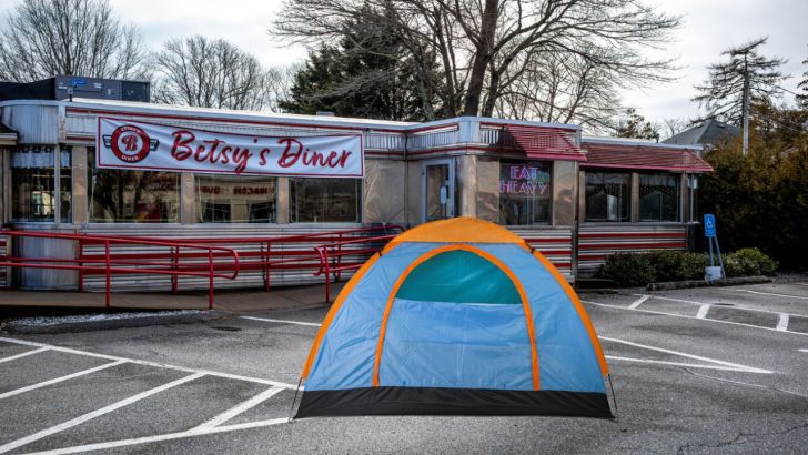 A tent set up for camping in the parking lot of a restaurant