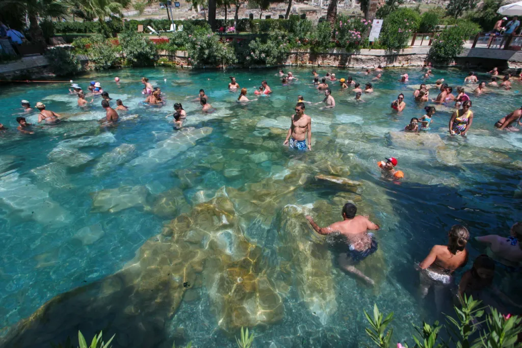 Group of people swimming a large hot spring. Large public hot springs tend not to allow nudity.