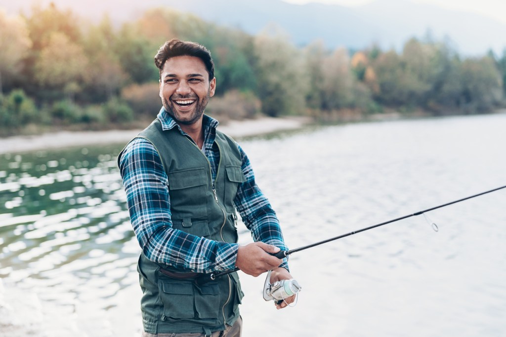 Smiling young man with fishing rod by the river. Fishing is popular at many of Kentucky's state resort parks.