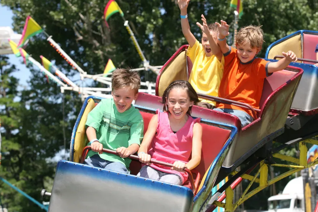 Kids on a carnival roller coaster. Kids of all ages will enjoy the amusement park rides.