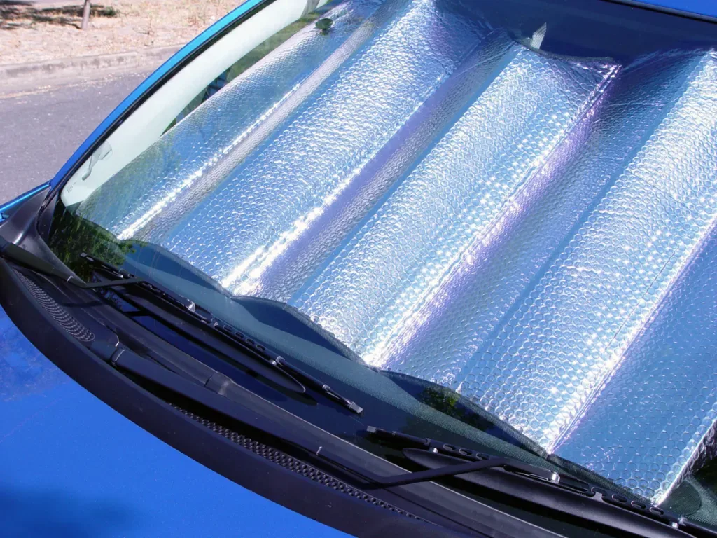 A silver accordion sun protector, unfolded within the windscreen of an Australian car.