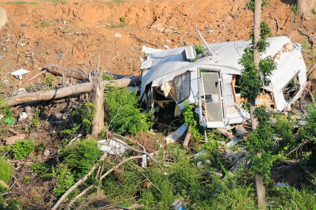 Small recreational vehicle completely destroyed by tornado with branches piercing the walls. RVs can be blown over by strong winds even if there's not a tornado in sight.