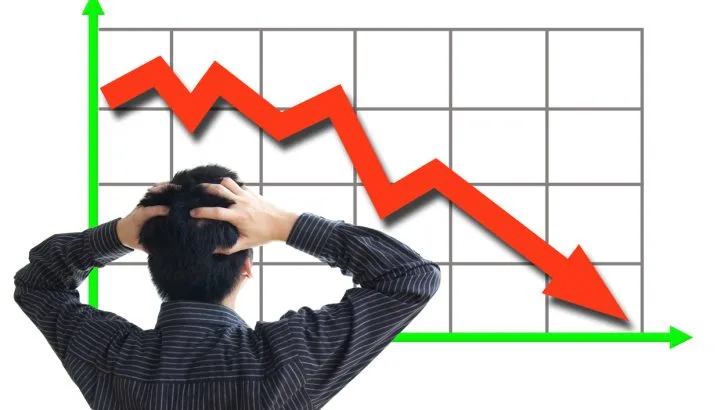 Frustrated business man looking at a graph with a down arrow.