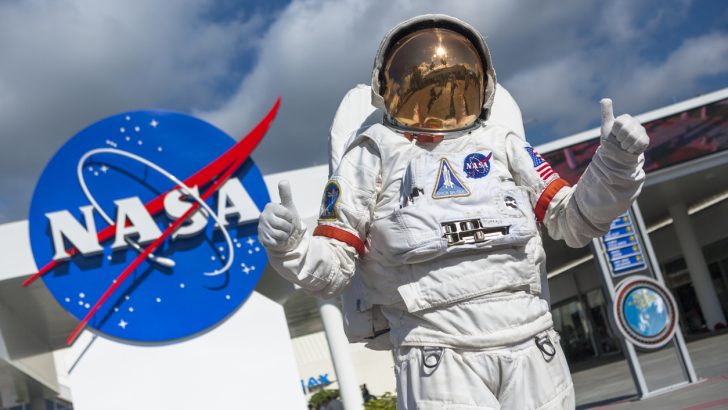 The NASA sign and an astronaut suit sit outside the Kennedy Space Center, which is a great day trip from Orlando, Florida.