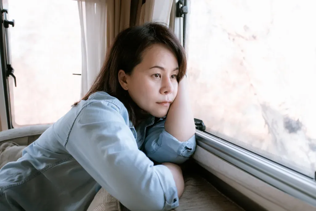 Lonely woman looking out the window in camper van. Burnout is a leading cause of people leaving the RV life.