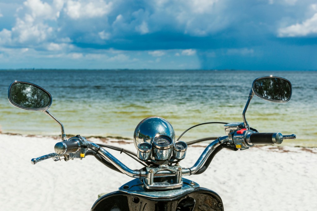 A motorcycle on a beach by the ocean. Some of Florida's best motorcycle rides take you alongside its famous beaches.