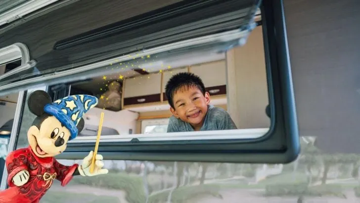 Mickey Mouse waving his wand over a young boy in an RV. Can you camp at Fort Wilderness?