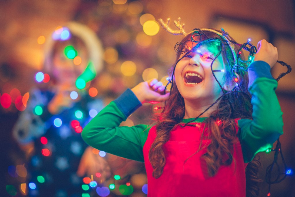 Little girl playing with holiday lights. We've got some great holiday decor ideas for a small budget!