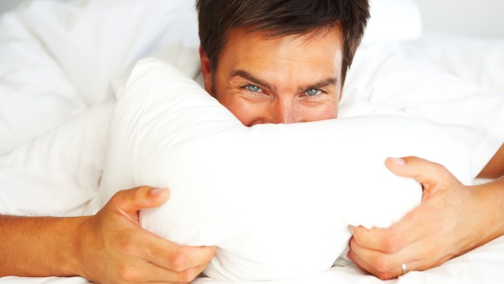 Young man holding a pillow to his face like he might with a booby pillow
