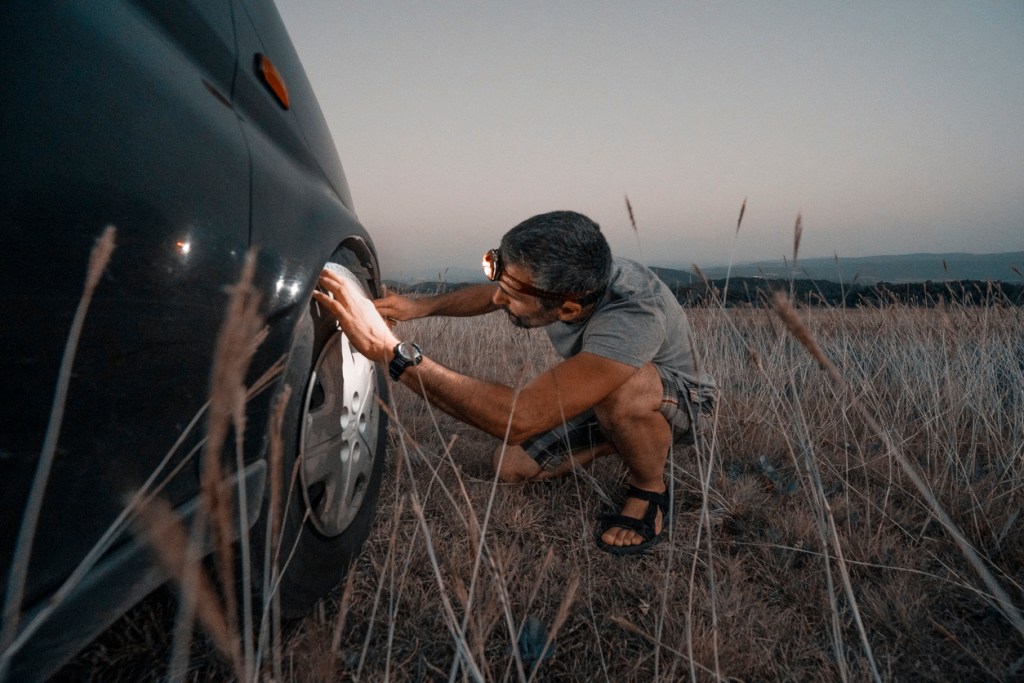 Man wearing a headlamp while checking his tire. Headlamp is an excellent RV accessory to have in your tool kit.