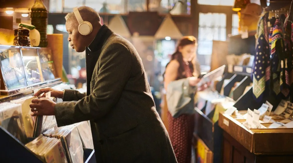 A man wearing headphones and looking through vinyl records at a record shop. The Tune Shop in Leavenworth, Kansas, is a great place to check out new music.