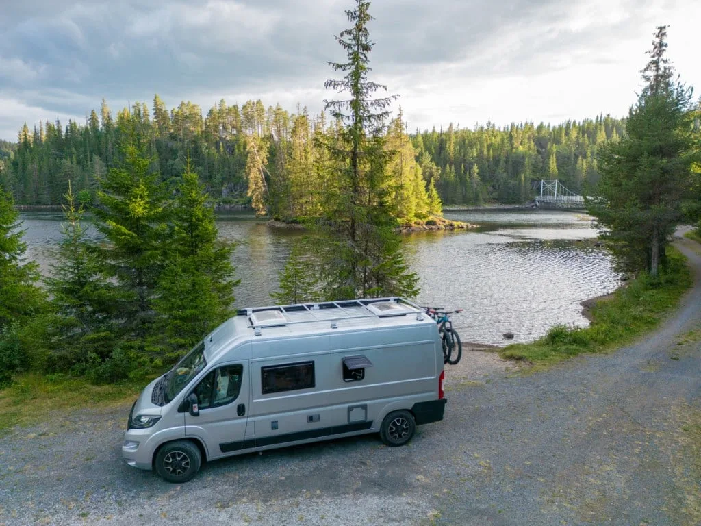 A class B camper parked next to a lake