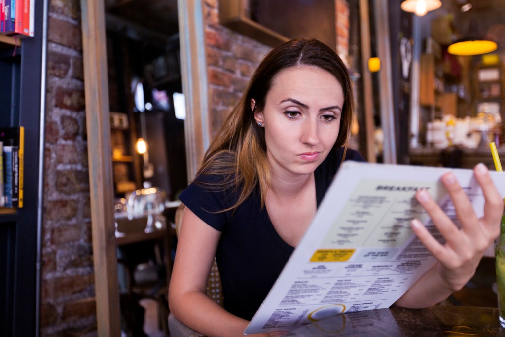 Beautiful young woman looking at menu like you'd find at Hard Rock Cafe