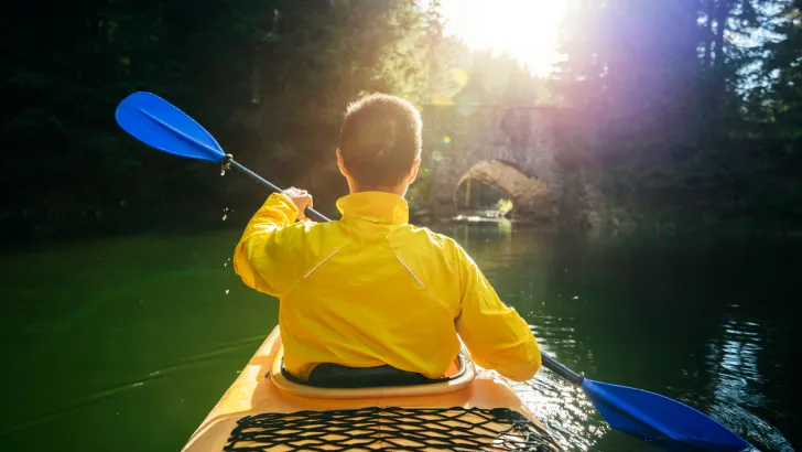 A person kayaking on a lake, possibly in a budget kayak