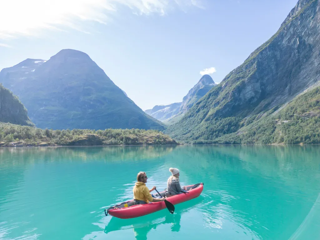 A couple kayaking on a lake surrounded by mountains, perhaps in a budget kayak.