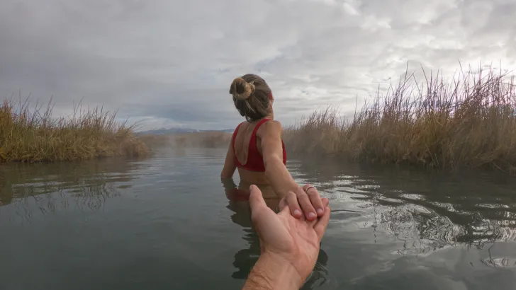 Woman pulling a man into hot springs