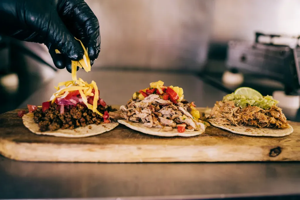 A chef sprinkling cheese on tacos